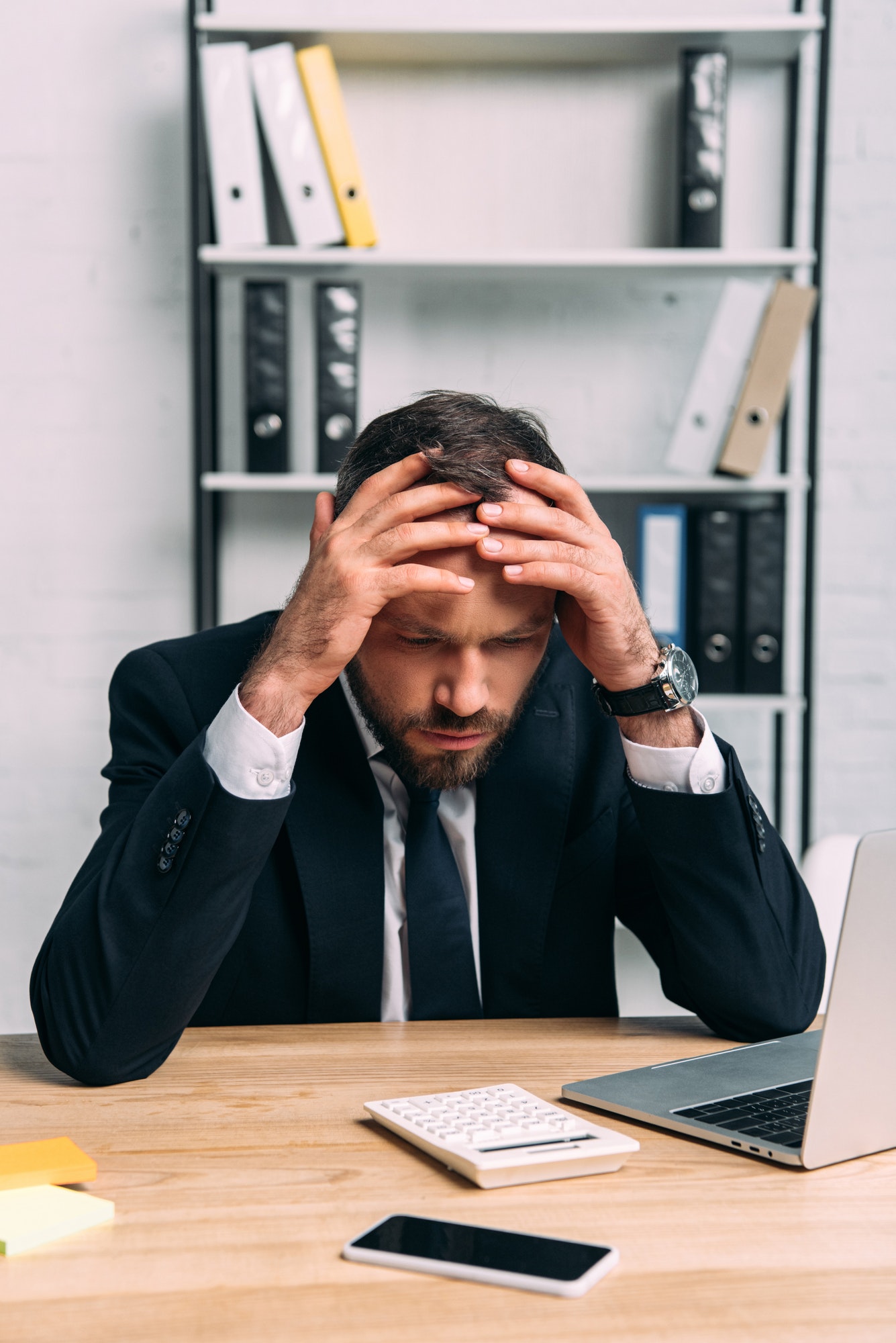 portrait of stressed businessman at workplace with laptop in office