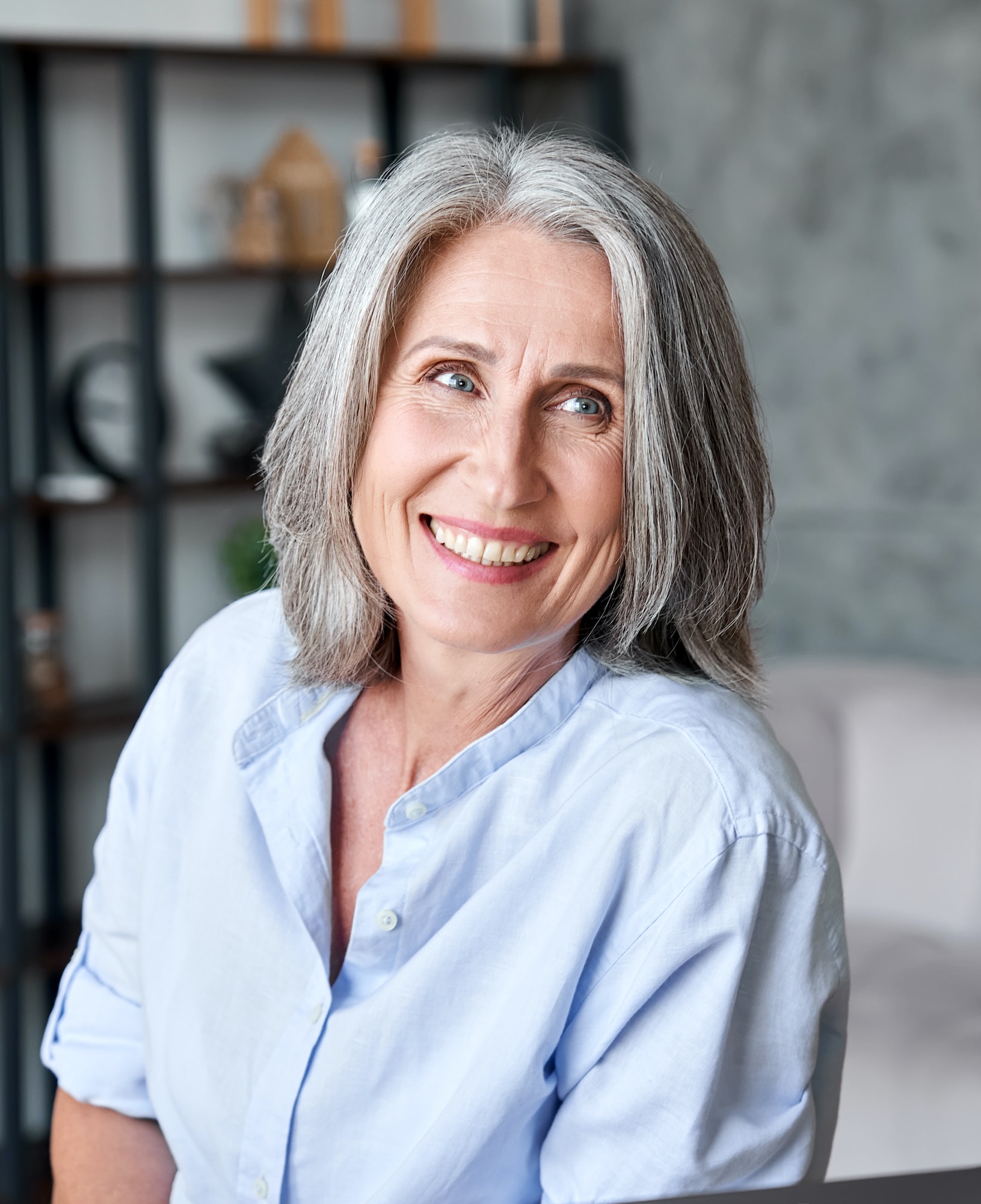 Happy beautiful old female businesswoman smiling looking away in office.